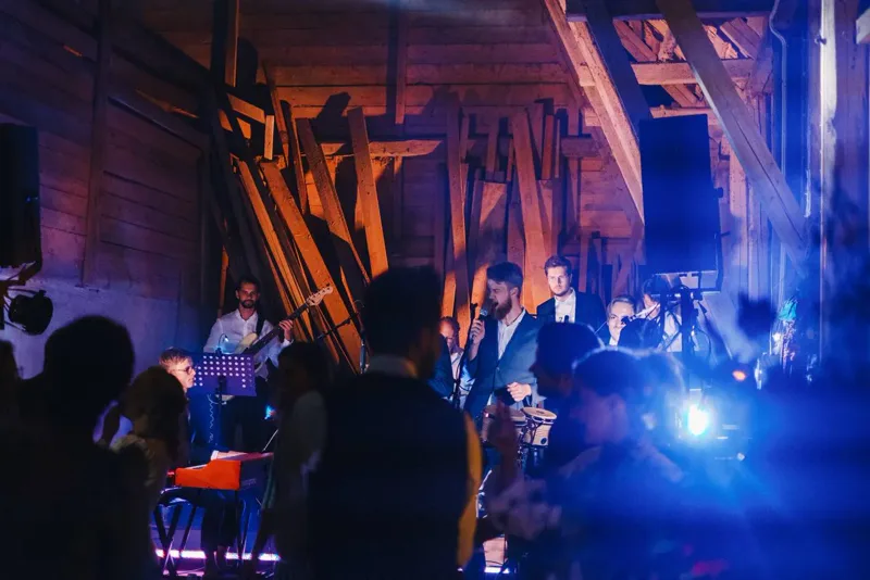 Band i rustik lokal med publik i silhuett och blå scenbelysning