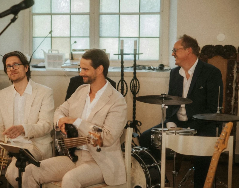 Musikgrupp i ljus lokal med bas, trummor och blås