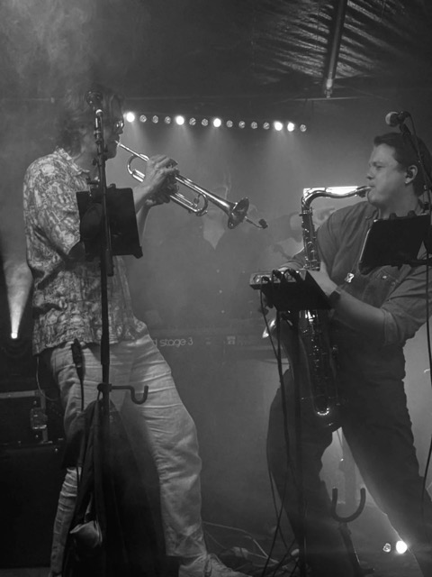 Trumpet och saxofon på scen i rök och scenljus